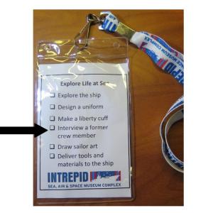 The back of the wearable badge includes checklist with small boxes to the left and text to the right that reads, "Explore the ship, design a uniform, make a liberty cuff, meet a former crewmember"
