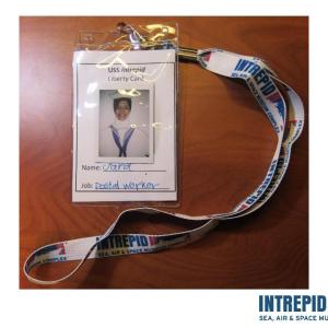 A wearable badge from the Intrepid Sea, Air, and Space Museum that includes a photograph of a person and her name and job with a lanyard attached