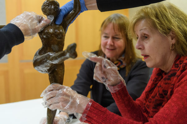 three visitors feel a bronze sculpture