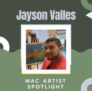 Jayson Valles looking at the camera, wearing a red shirt, with sunglasses hanging from the collar of his shirt. His painting of a city landscape at night is on an easel behind him.